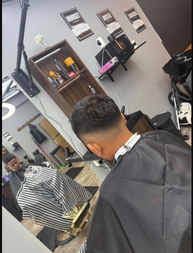 The back of a clean skin fade at Fade Shack Barbers, Orewa, with another client waiting in the mirror behind.